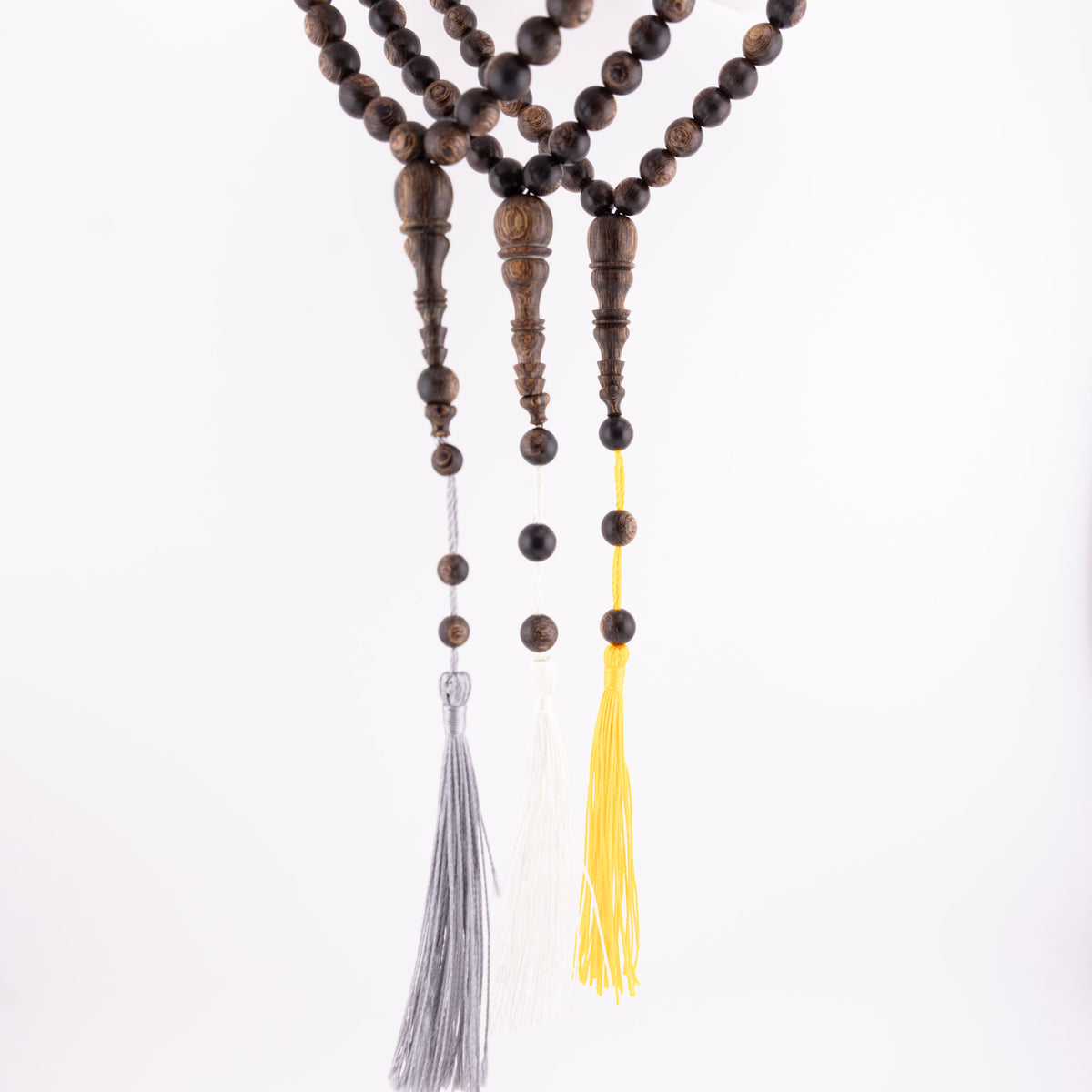 Buy agarwood prayer beads shown as three 33-bead strands with grey, white, and yellow tassels