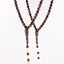 Long agarwood prayer beads displayed as two 99-bead strands with yellow and white cords