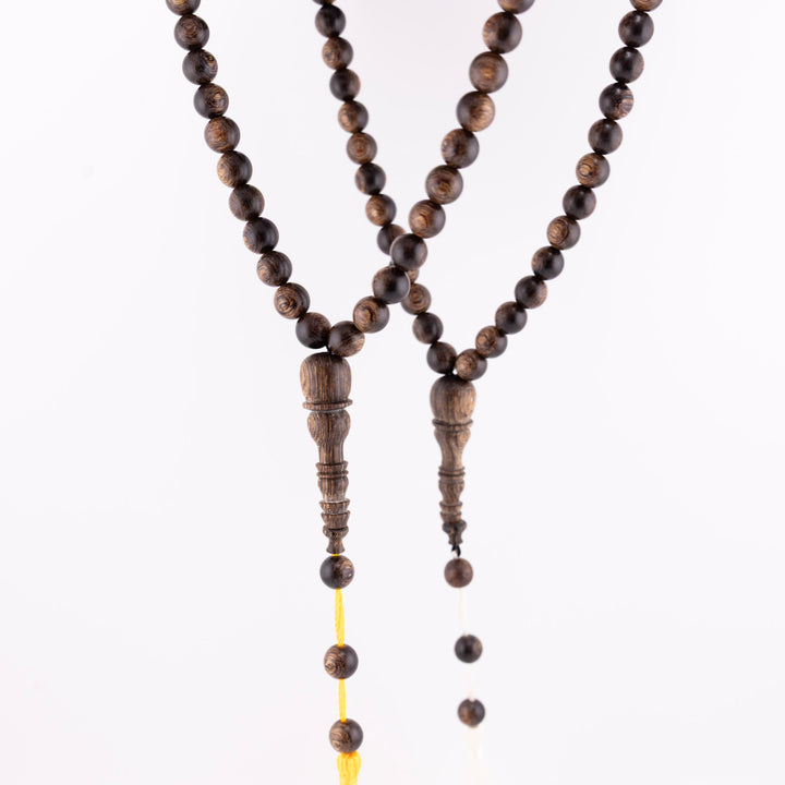 Long agarwood prayer beads displayed as two 99-bead strands with yellow and white cords