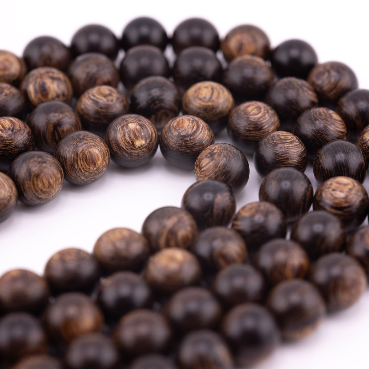 Long agarwood prayer beads shown close up with dark brown tones and varied wood grain