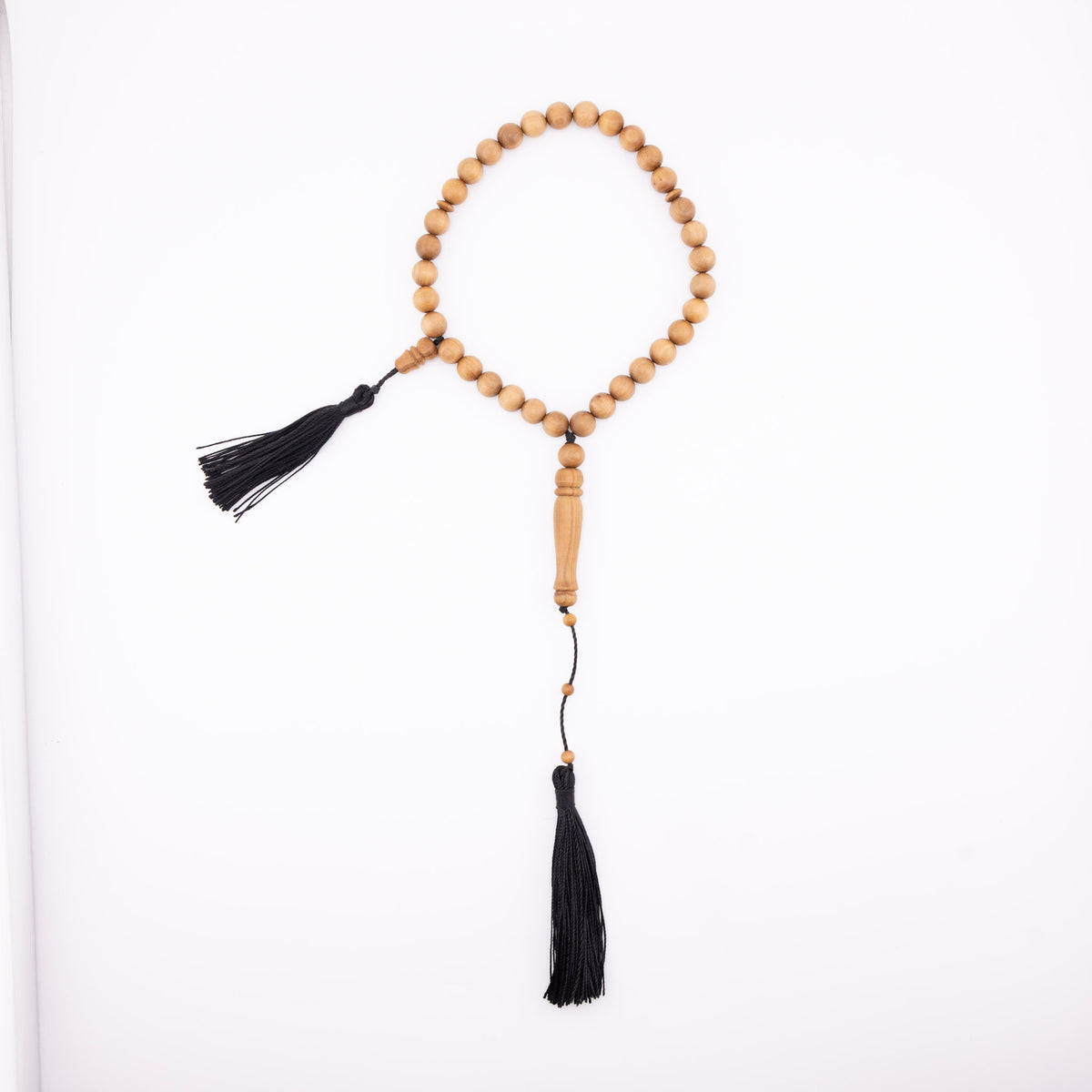 Sandalwood prayer strand for sale with 33 beads, black tassels, and a carved wooden centerpiece