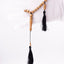 Sandalwood prayer strand for sale held in a white-gloved hand with black tassels visible