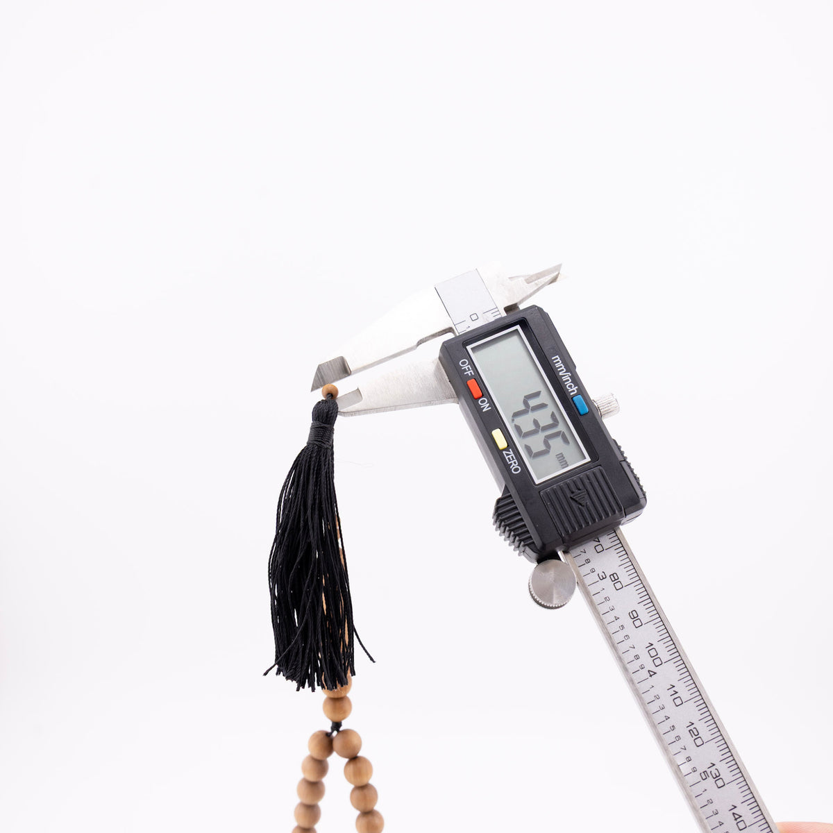 Sandalwood prayer strand for sale with a small bead measured beside the black tassel