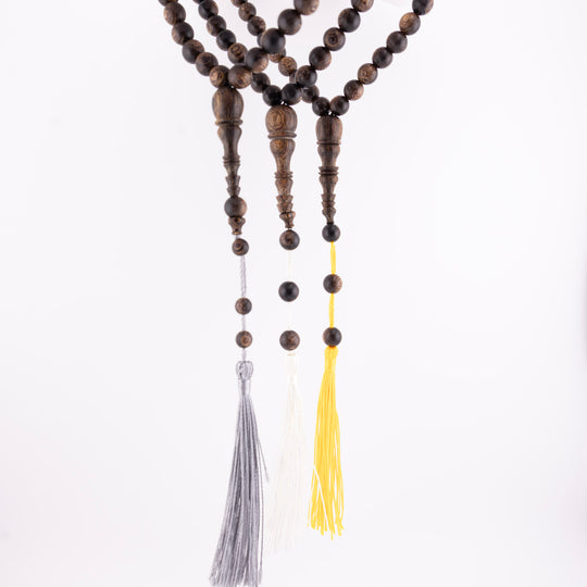 Buy agarwood prayer beads shown as three 33-bead strands with grey, white, and yellow tassels