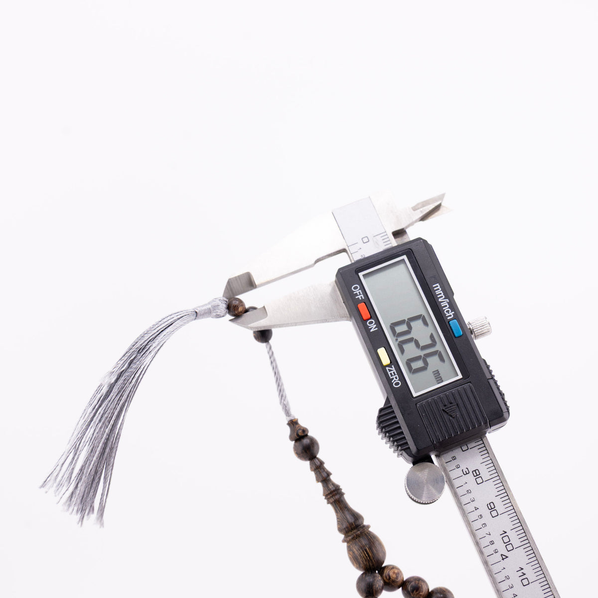 Buy agarwood prayer beads with one bead measured beside the grey tassel