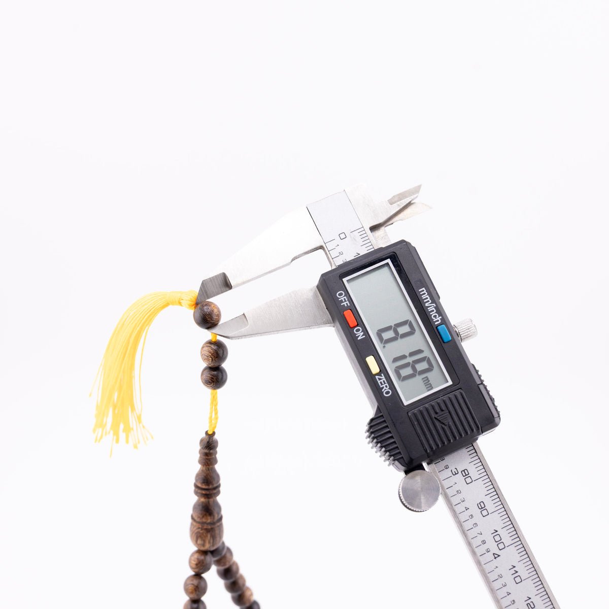 Buy agarwood prayer beads with one bead measured beside the yellow tassel