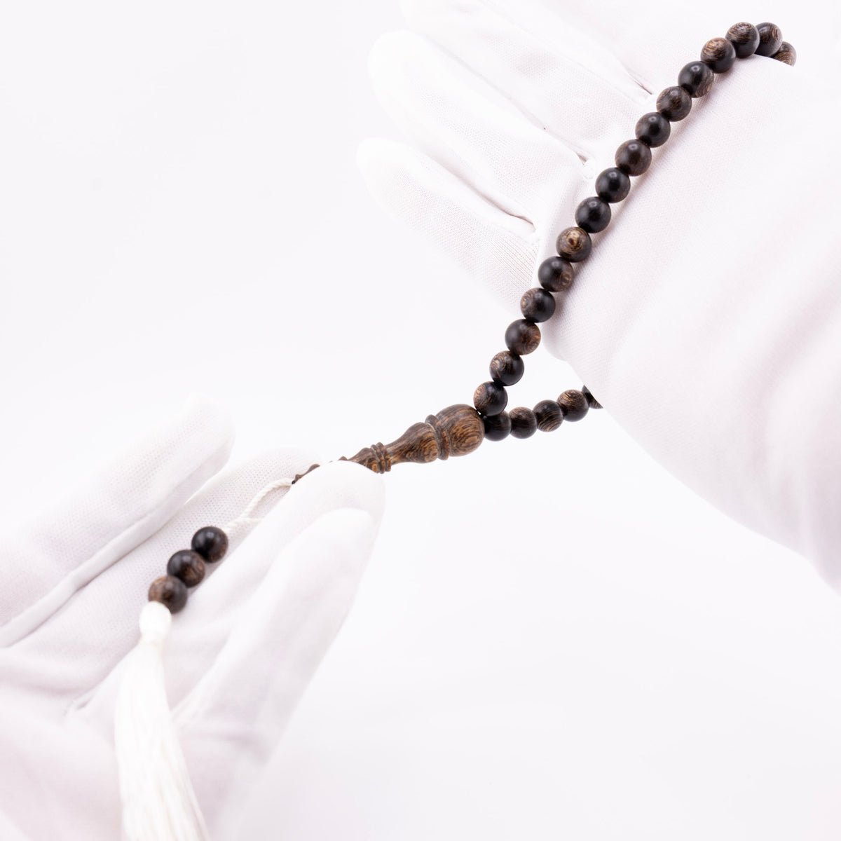 Buy agarwood prayer beads with white cord held between white-gloved hands