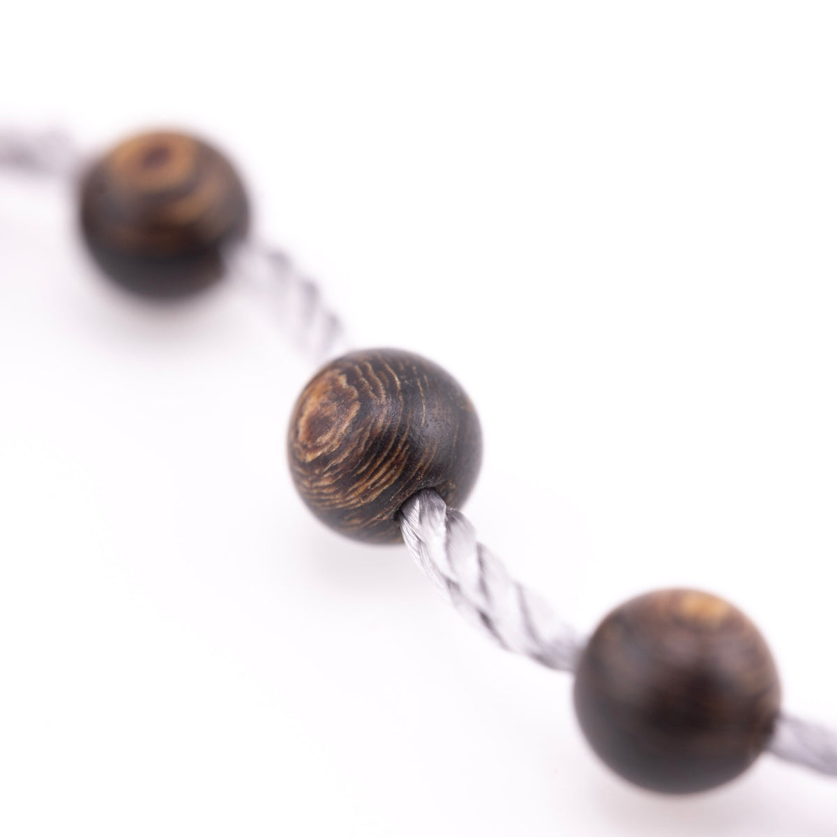 Buy agarwood prayer beads shown in a macro view threaded onto grey cord