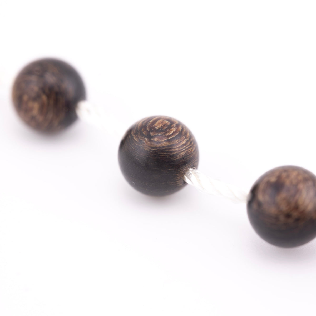 Buy agarwood prayer beads shown in a macro view threaded onto white cord