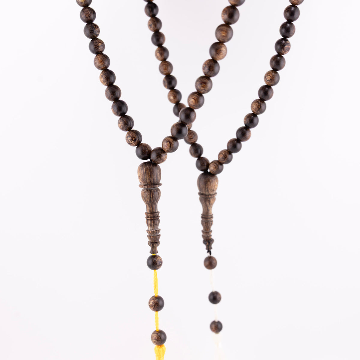 Long agarwood prayer beads displayed as two 99-bead strands with yellow and white cords