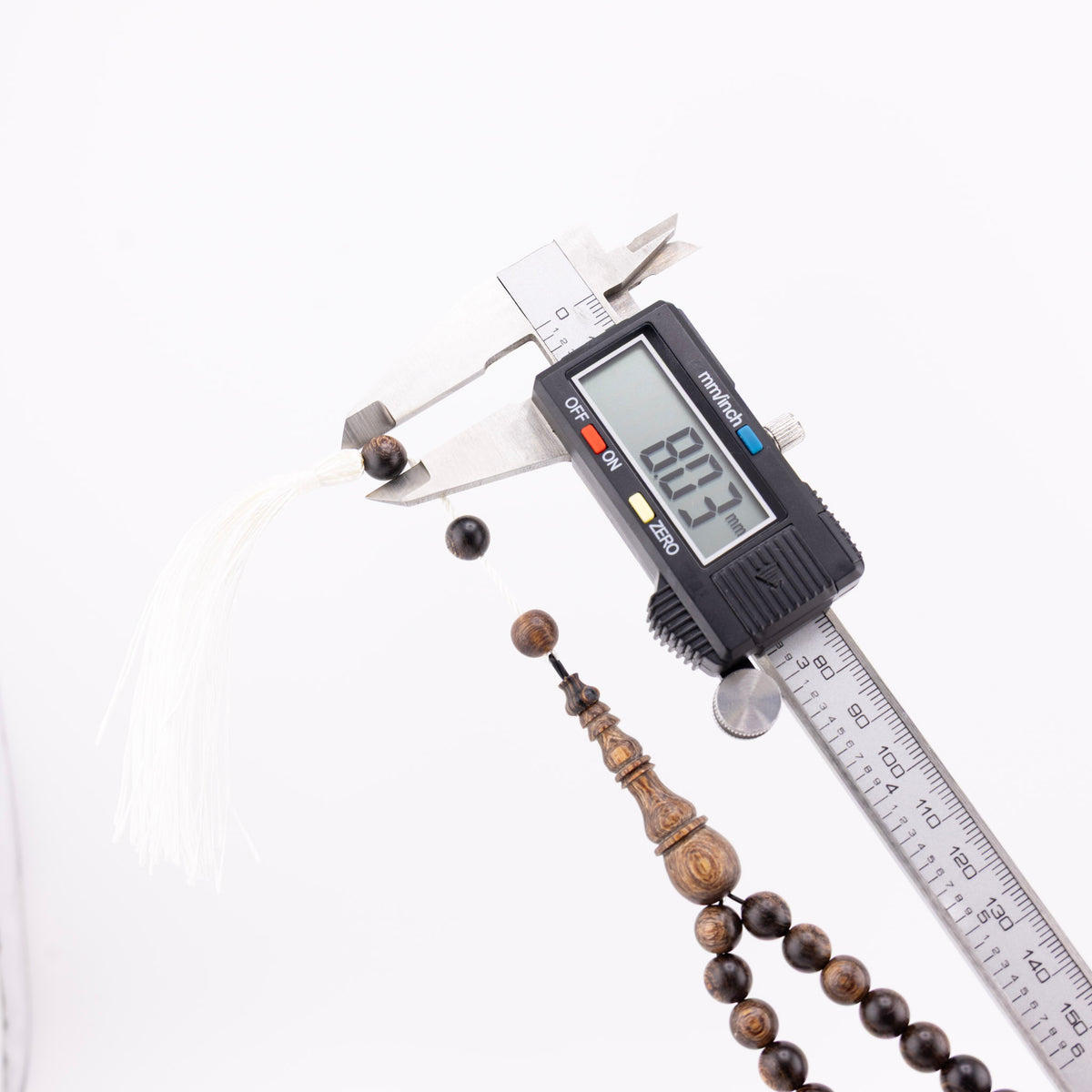 Long agarwood prayer beads with one bead measured beside the white tassel