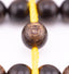 Long agarwood prayer beads in a macro view of one bead threaded onto yellow cord