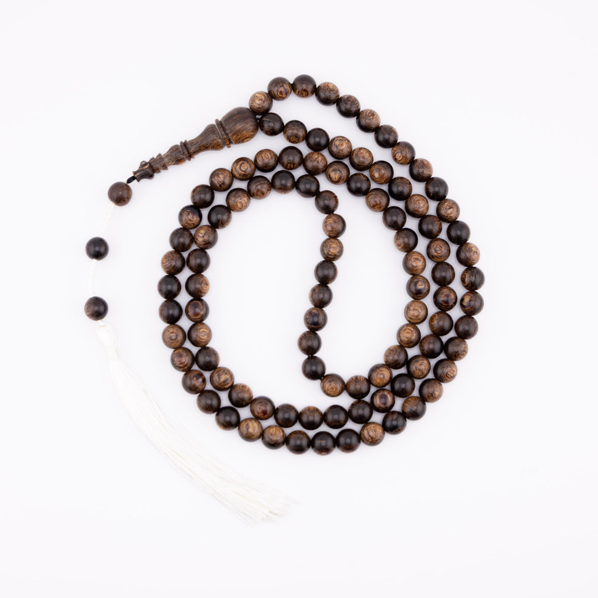 Long agarwood prayer beads coiled on a white background with a white tassel