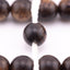 Long agarwood prayer beads in a macro view of one bead threaded onto white cord
